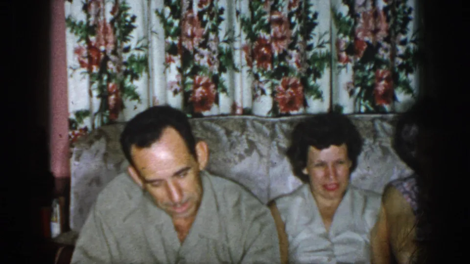 1958 Dayton frame showing adults seated on a couch, including a man looking down and a woman facing forward.