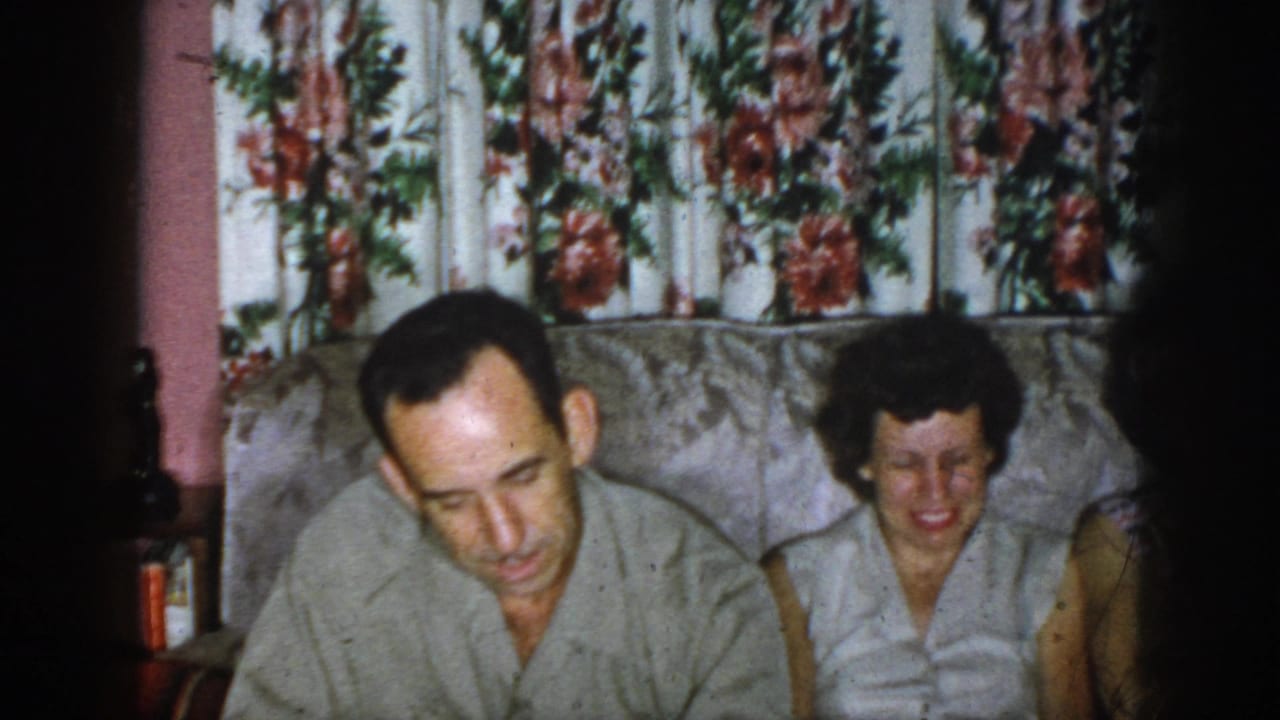 Man and woman on a sofa, with another partially visible person at the right edge.