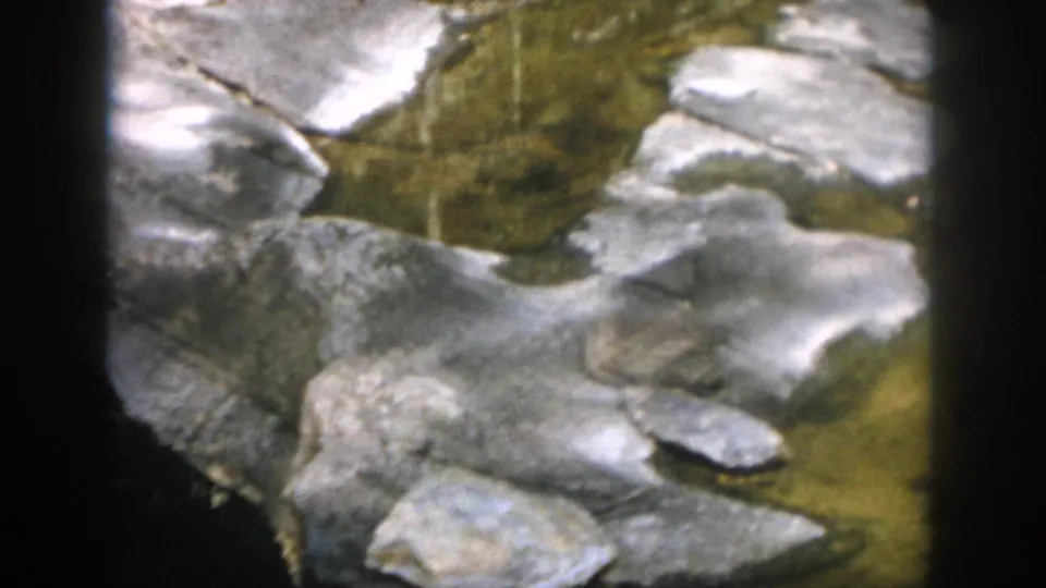 1958 Dayton, Ohio 8mm frame showing flat creek stones, clear water, and small standing pools.