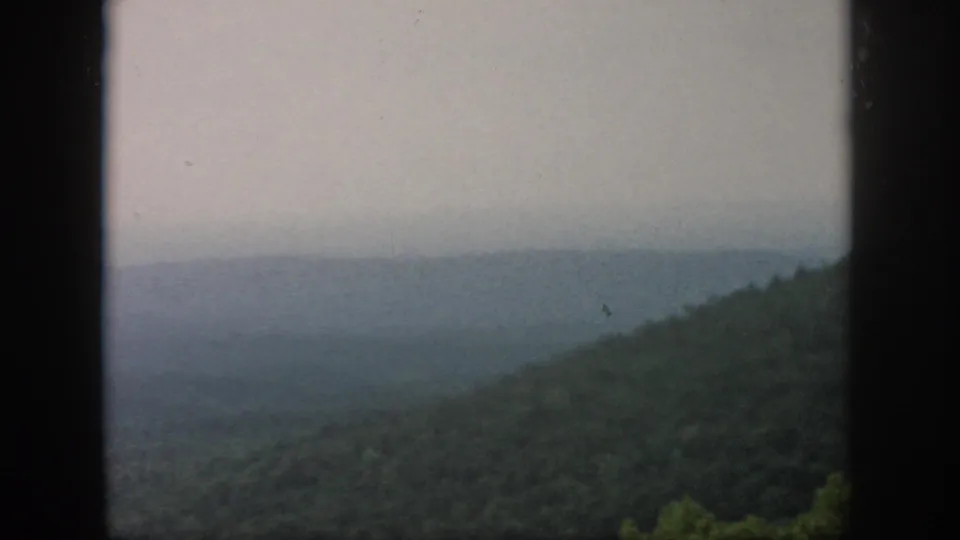 A soft 8mm view of wooded Ohio hills and a foggy valley distance, bordered by dark window-frame shapes.