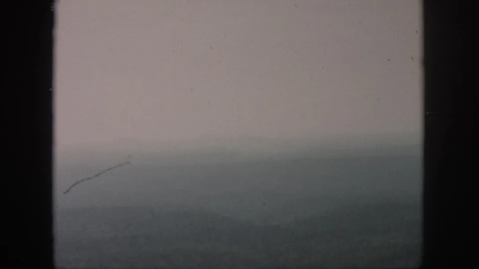 A faded 8mm landscape frame shows a nearly abstract foggy valley, distant ridge, and dark window edge.
