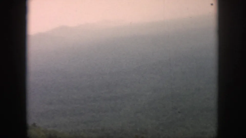 1958 8mm home-movie frame from the Dayton, Ohio metadata context showing misty hills through an airplane window.