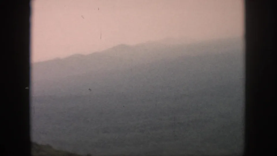 A muted 1958 aerial travel view shows layered hills and a valley through the aircraft window frame.