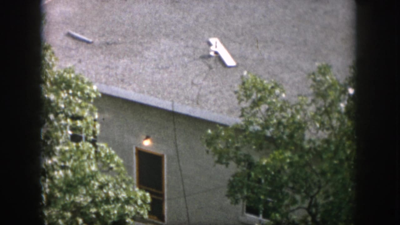 1958 Dayton residential roofline viewed through trees, showing a small white television antenna on the shingled roof.