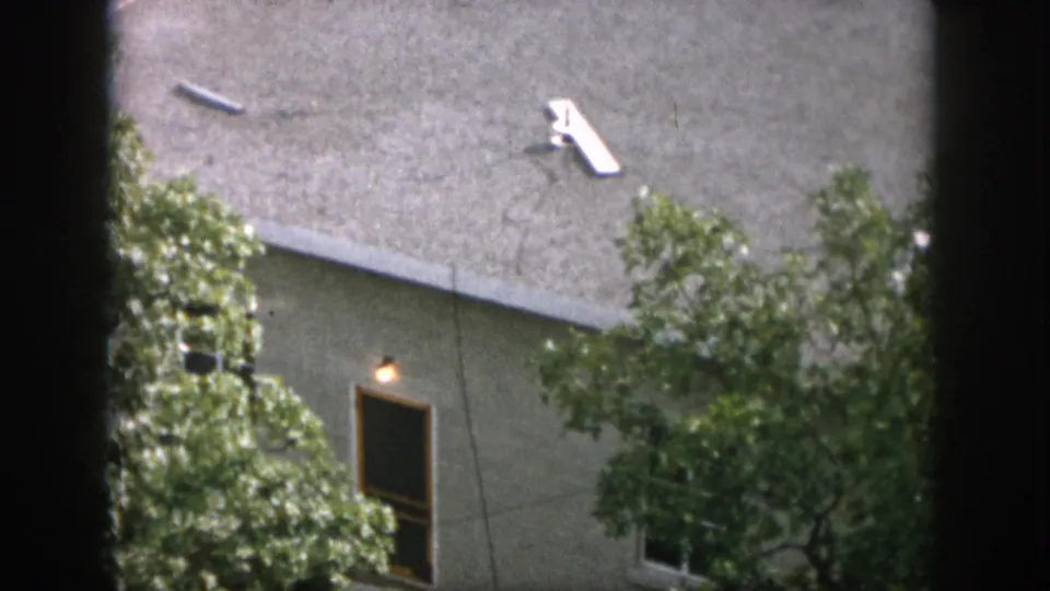 1958 Dayton residential roofline viewed through trees, showing a small white television antenna on the shingled roof.