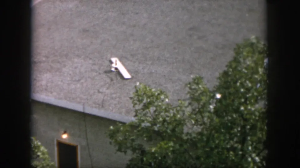 1958 Dayton home-movie view of a rooftop television antenna above a suburban doorway and surrounding tree branches.