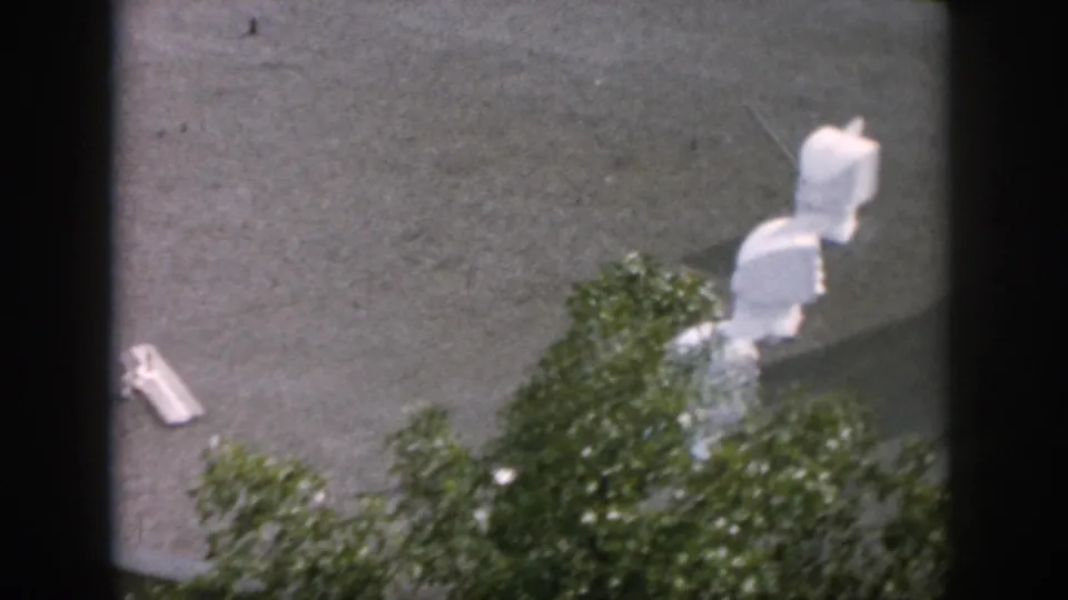 1958 Dayton home-movie frame focused on rooftop antenna hardware, roof shingles, and foliage along the lower edge.
