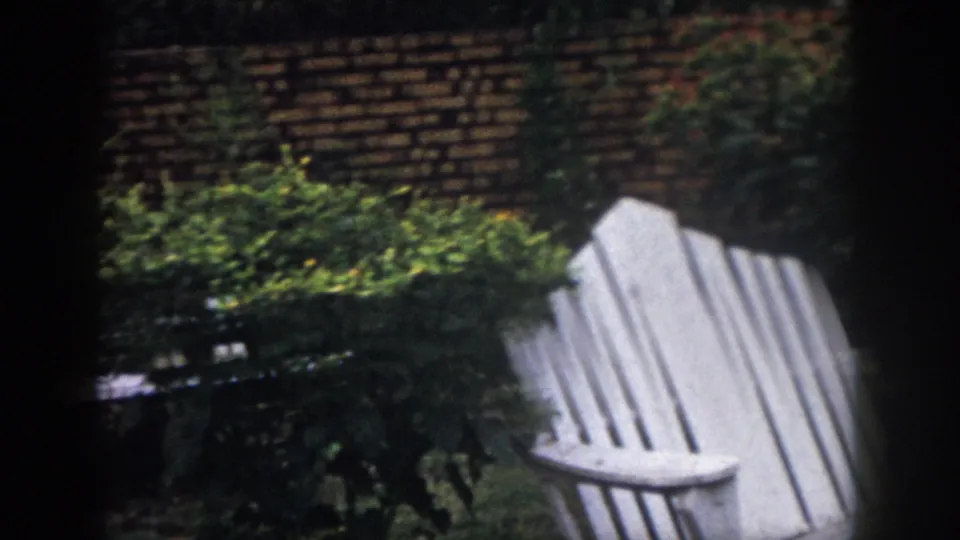 1958 Dayton garden frame showing a white outdoor chair near shrubs, with dark window-like edges in the scan.