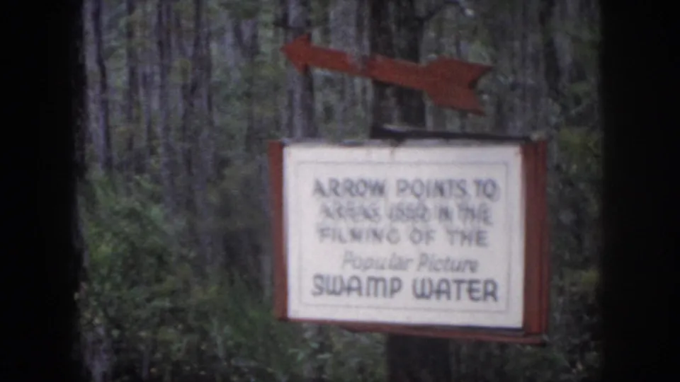 1958 Dayton, Ohio frame showing the sign and arrow for Swamp Water filming areas, softened by 8mm focus and grain.