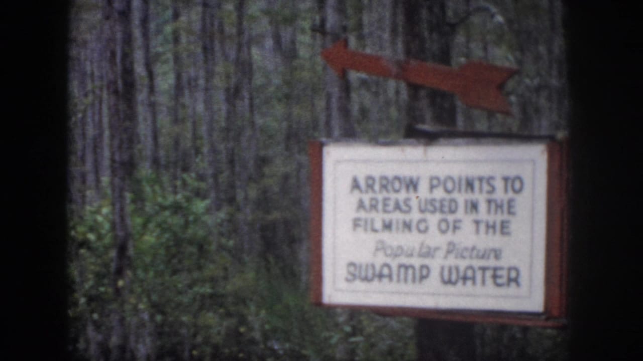 1958 Dayton, Ohio 8mm frame showing a red-arrow sign for Swamp Water filming areas among trees and foliage.