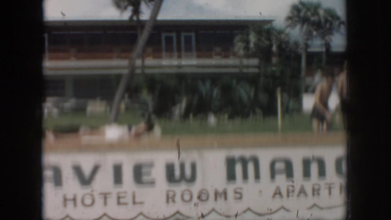 1958 New Orleans home-movie frame showing the View Manor Hotel and Apartments sign, palm trees, lawn, and building facade.