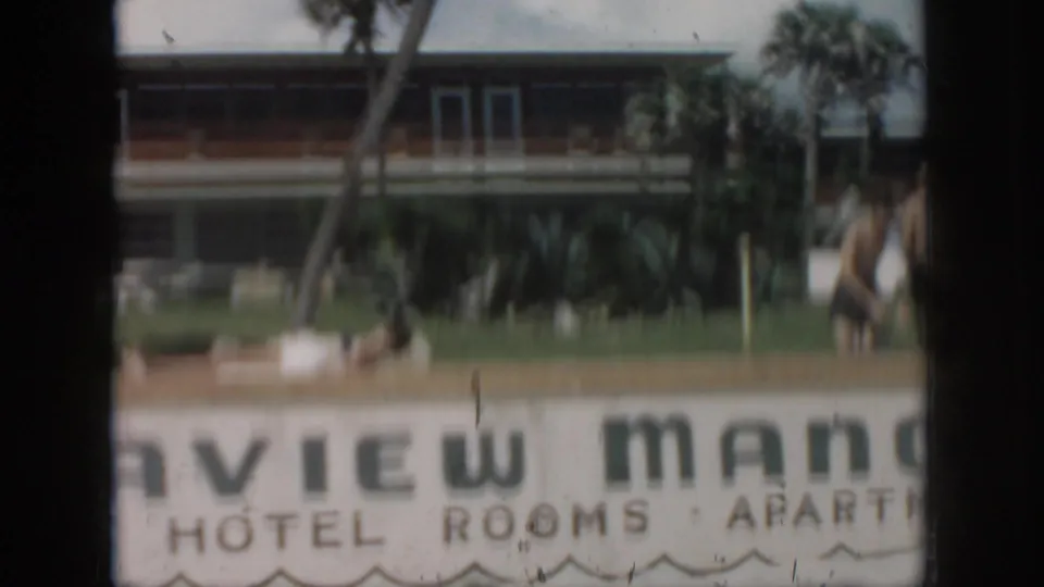 1958 New Orleans home-movie frame showing the View Manor Hotel and Apartments sign, palm trees, lawn, and building facade.