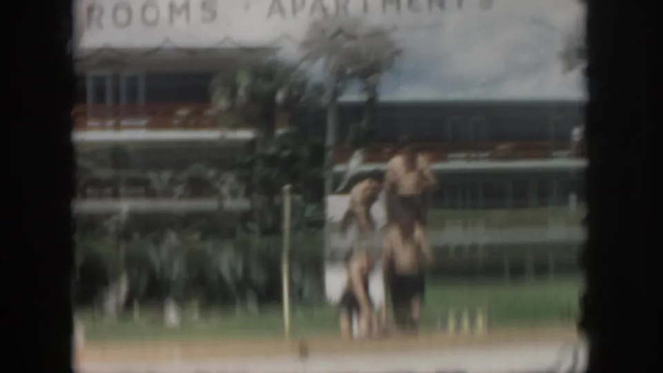 1958 New Orleans home-movie frame showing people in swimwear on the lawn near the View Manor hotel-apartment exterior.