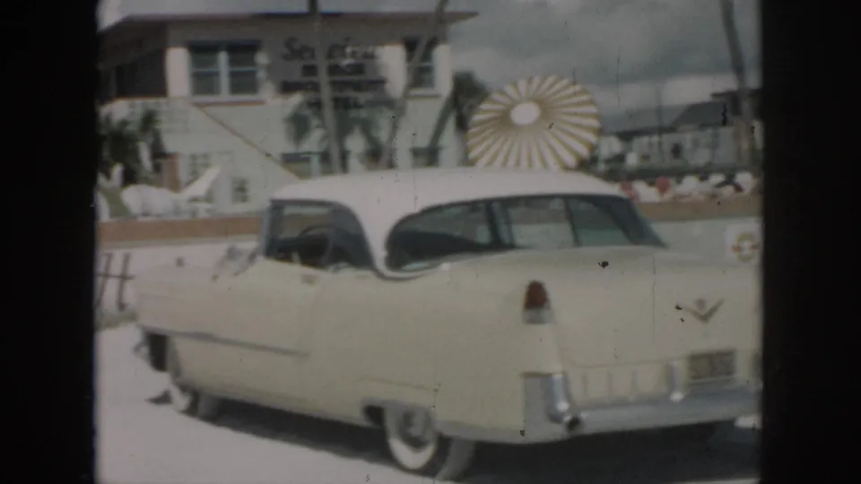 1958 New Orleans home-movie view of the rear of a cream classic car outside the Sea View Motor Inn Apartment Hotel.