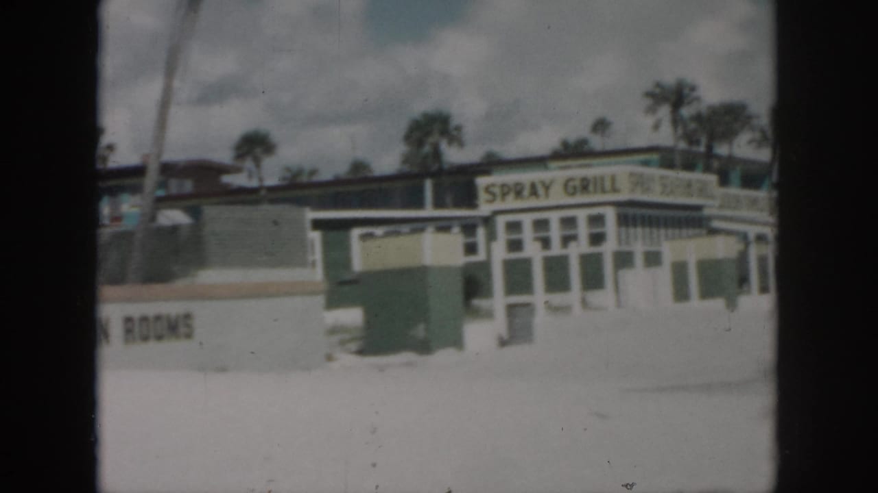 Spray Grill building beside a TV in Rooms sign, with palm trees in the background.
