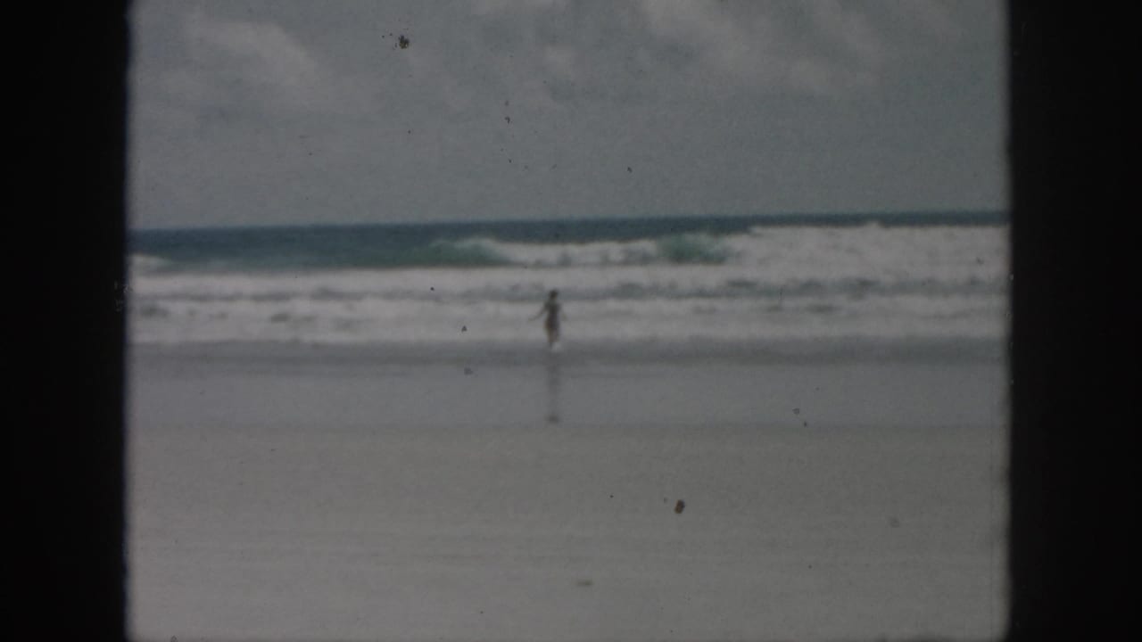 Small figure near the shoreline with waves rolling in across a wide sandy beach.