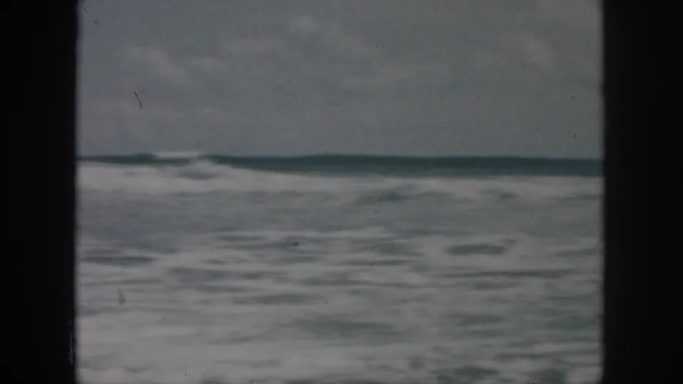 1958 home-movie frame of open ocean waves and horizon, with faded color and 8mm frame borders.