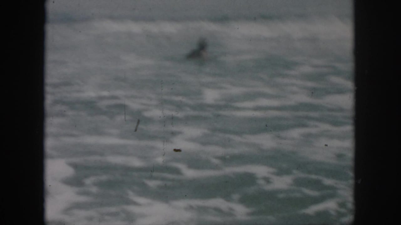 Foamy ocean water with a distant swimmer near the upper frame.