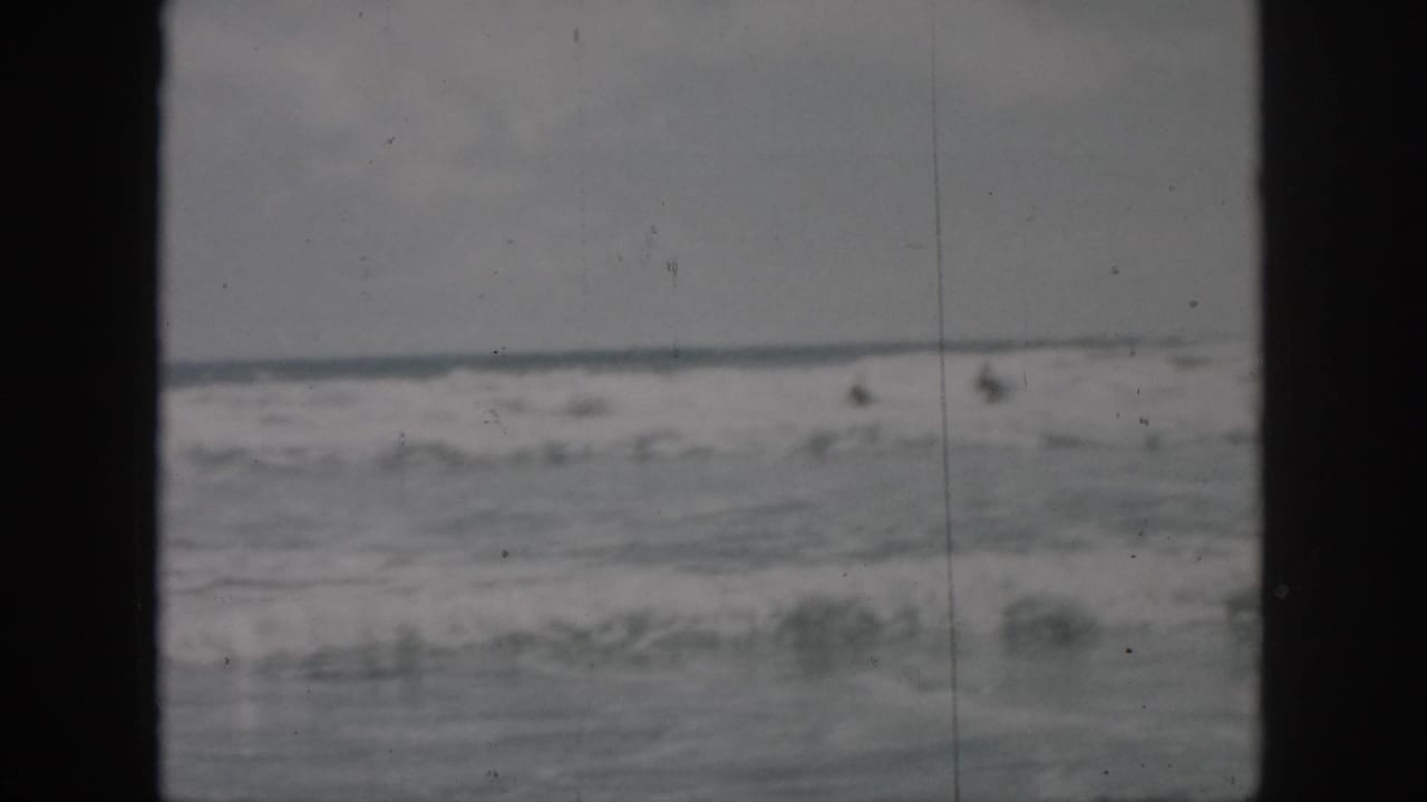 Choppy ocean waves under a gray sky with dark 8mm frame borders.