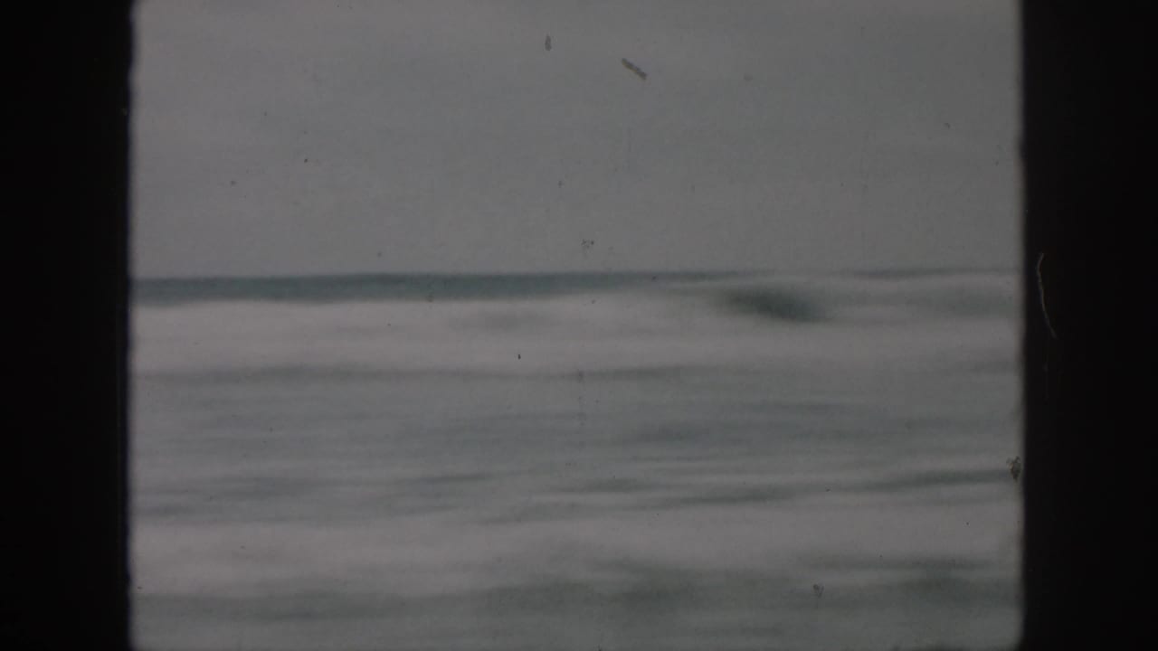 Blurred surf and horizon seen through a dark vertical film border.