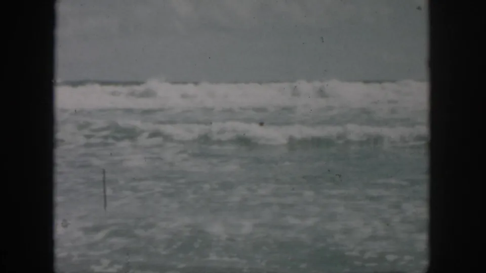 1958 8mm home-movie frame showing rough ocean surf near New Orleans, Louisiana, with no clear figures in the water.