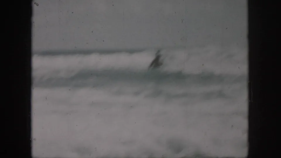 Soft 1958 8mm frame showing a swimmer partly obscured by foamy waves near a beach in the New Orleans, Louisiana area.