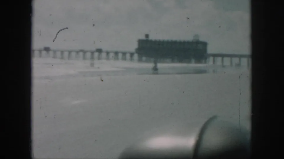 1958 New Orleans home-movie view of a distant pier over breaking surf, with beach and soft, faded 8mm color.