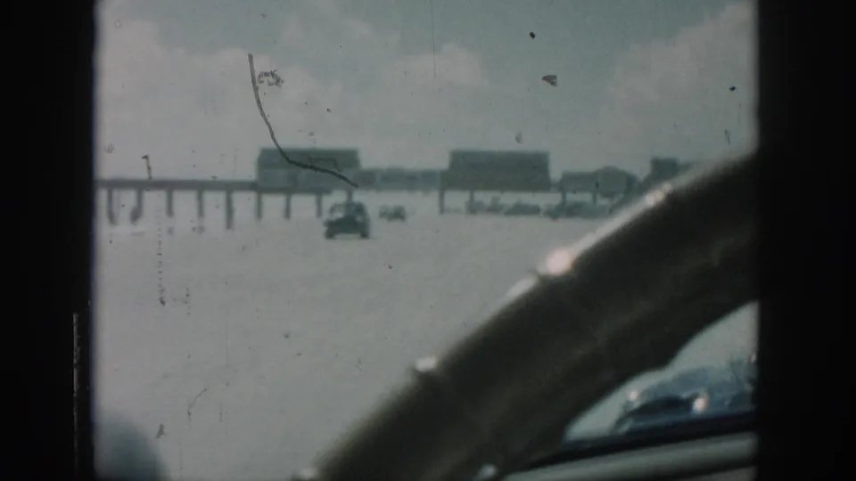 1958 New Orleans flooded roadway seen from inside a car, with another automobile crossing the water ahead.