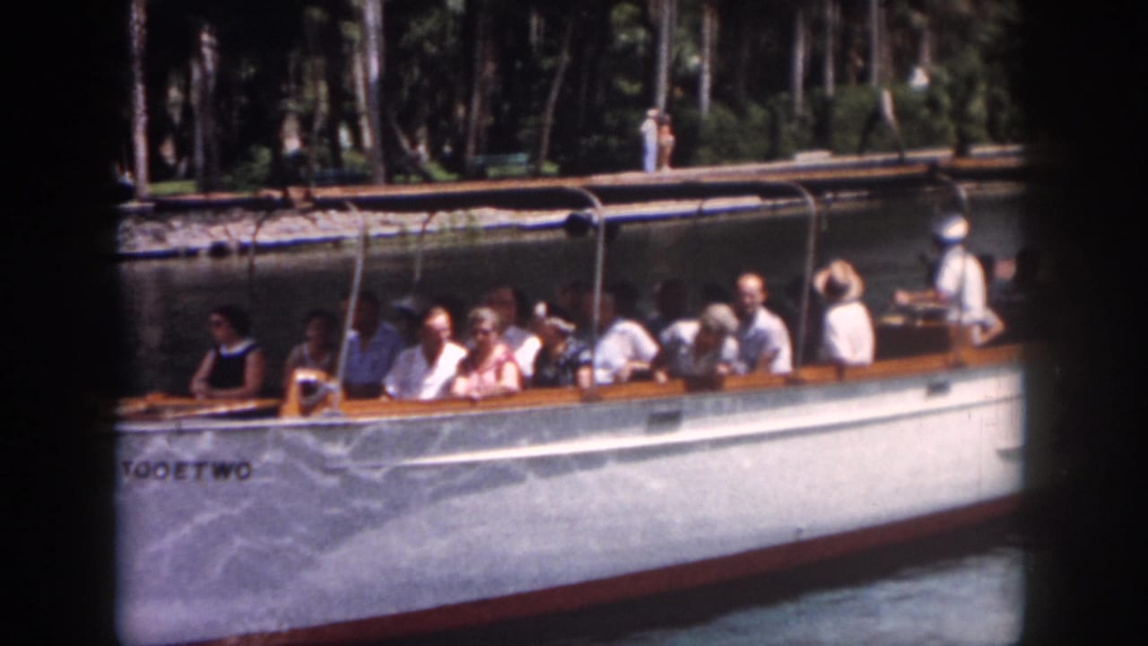 1958 New Orleans footage frame with tourists in summer clothing aboard the boat TOOETWO on a shaded waterway.