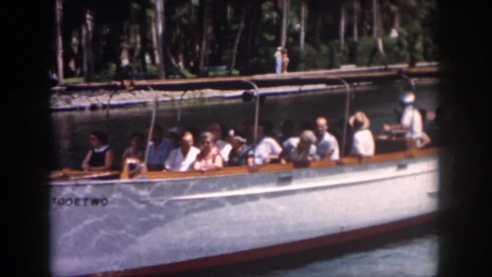 1958 New Orleans footage frame with tourists in summer clothing aboard the boat TOOETWO on a shaded waterway.