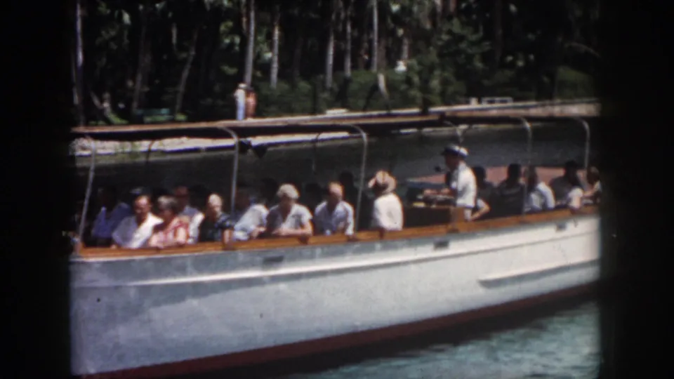 Home-movie frame from New Orleans in 1958 showing a side view of tourists seated on a white canal boat.