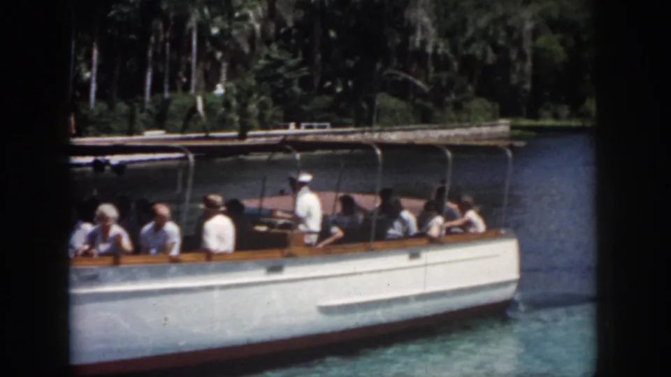 1958 New Orleans 8mm frame showing the tour boat farther down the waterway beside a wooded park-like bank.
