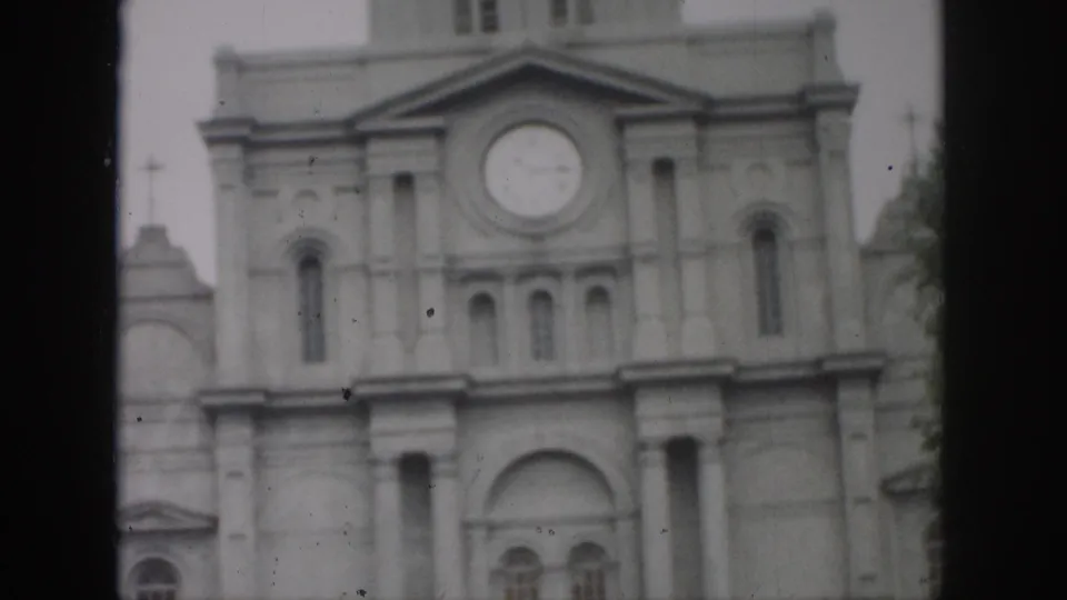 1958 New Orleans home-movie frame centered on the building's clock, pediment, arched windows, and columned facade.