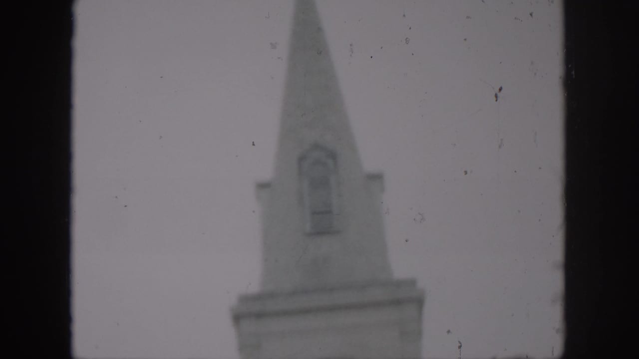 1958 New Orleans home-movie frame showing the upper steeple of St. Louis Cathedral in soft focus with dark gate borders.