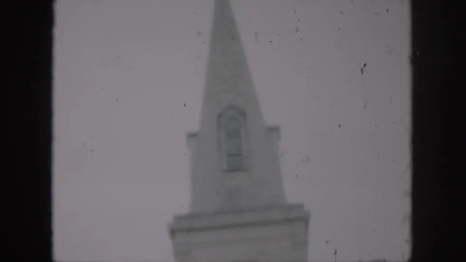 1958 New Orleans home-movie frame showing the upper steeple of St. Louis Cathedral in soft focus with dark gate borders.