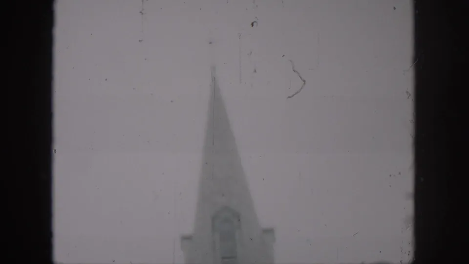 St. Louis Cathedral steeple appears in a soft 1958 New Orleans frame, partly obscured by the 8mm gate edge.