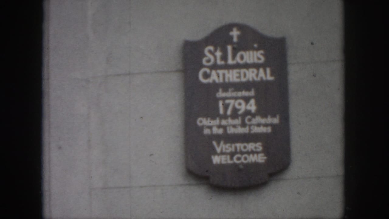 St. Louis Cathedral sign repeated in soft focus on a stone wall.
