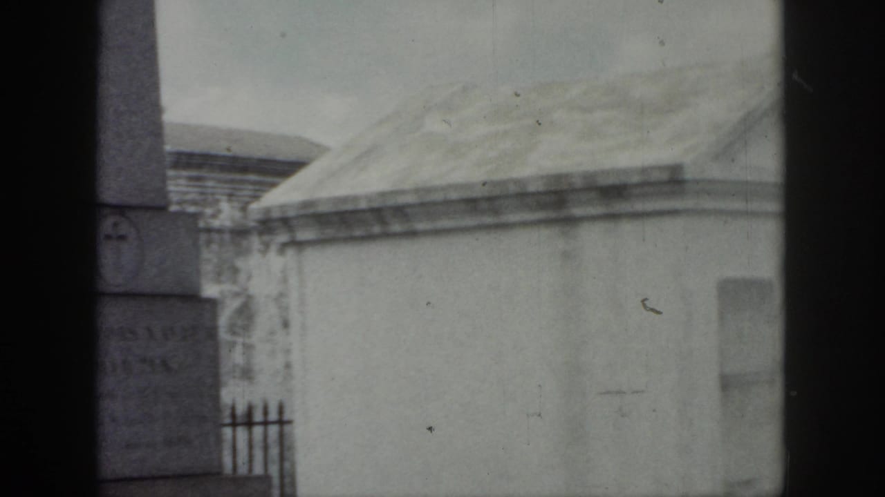Stone monument and pale mausoleum roof seen through dark 8mm frame borders.