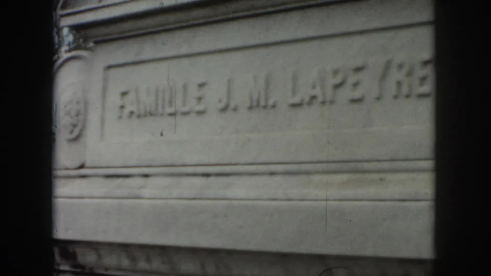 1958 New Orleans 8mm still showing the tomb inscription “FAMILLE J. M. LAPE...” across a weathered stone panel.
