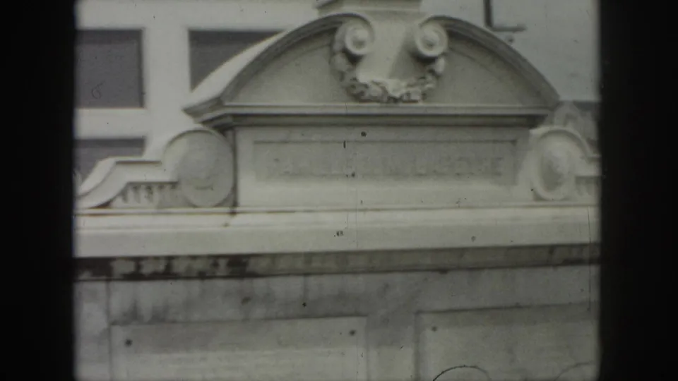 1958 New Orleans frame showing a wider view of the J. M. LAPEYRE memorial top with arched stonework and surrounding architectural edges.