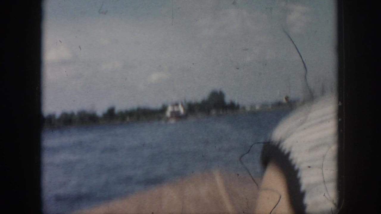 Open water and distant shoreline with a partial woman’s profile at the right edge.