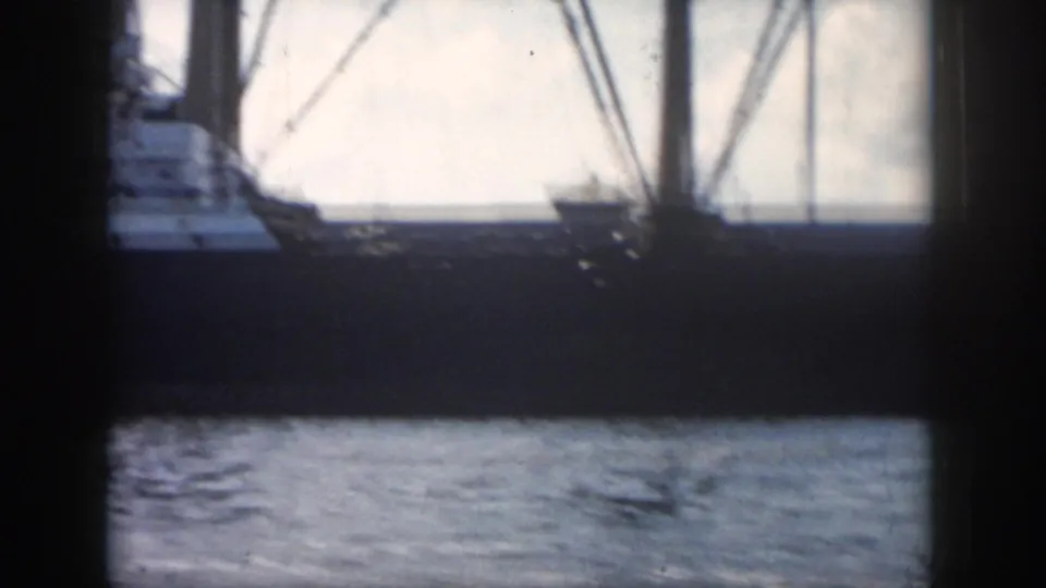 A partly cropped 1958 New Orleans frame shows the vessel's side, deckhouse, rigging, and water below in faded 8mm color.