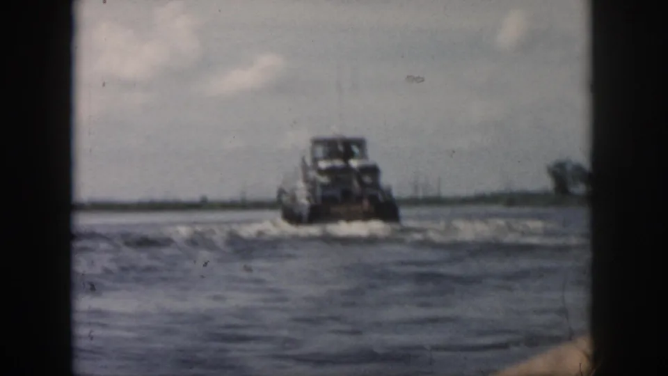 1958 New Orleans-area 8mm frame showing a small motorboat speeding over choppy water under a cloudy sky.
