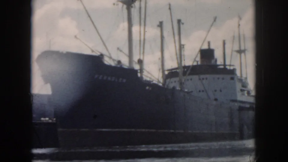 1958 New Orleans harbor view of a cargo ship with a dark hull, white superstructure, masts, and visible name lettering.