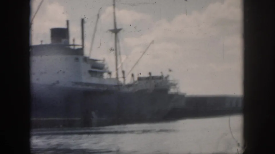 1958 New Orleans harbor view of the rear portion of a cargo ship, with deck structures, masts, water, and a low port wall.