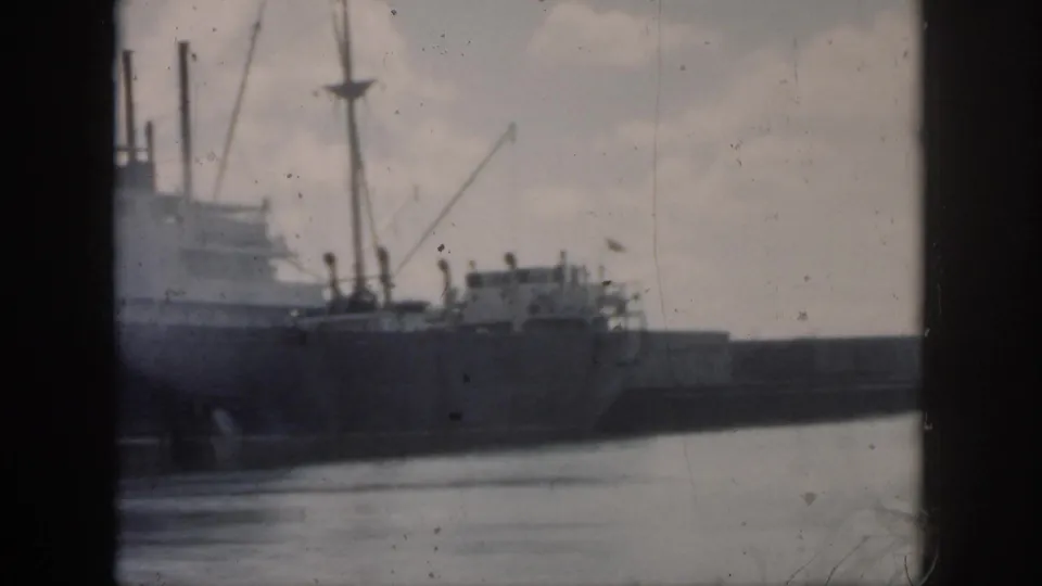 1958 New Orleans harbor frame with the ship's stern area, rigging, low wall, and rippled water from passing boat movement.