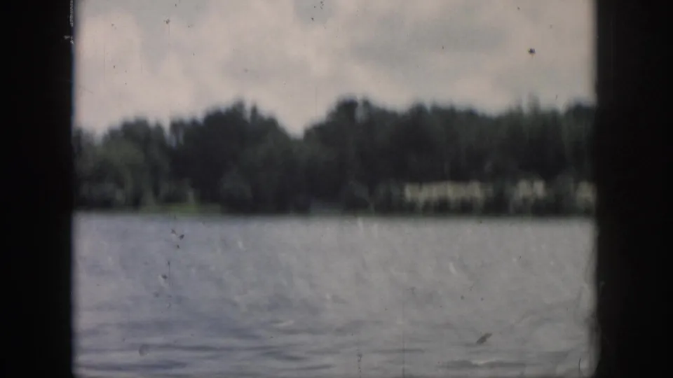 Soft 8mm view of a broad New Orleans-area waterway with shoreline trees and cloudy sky in the distance.