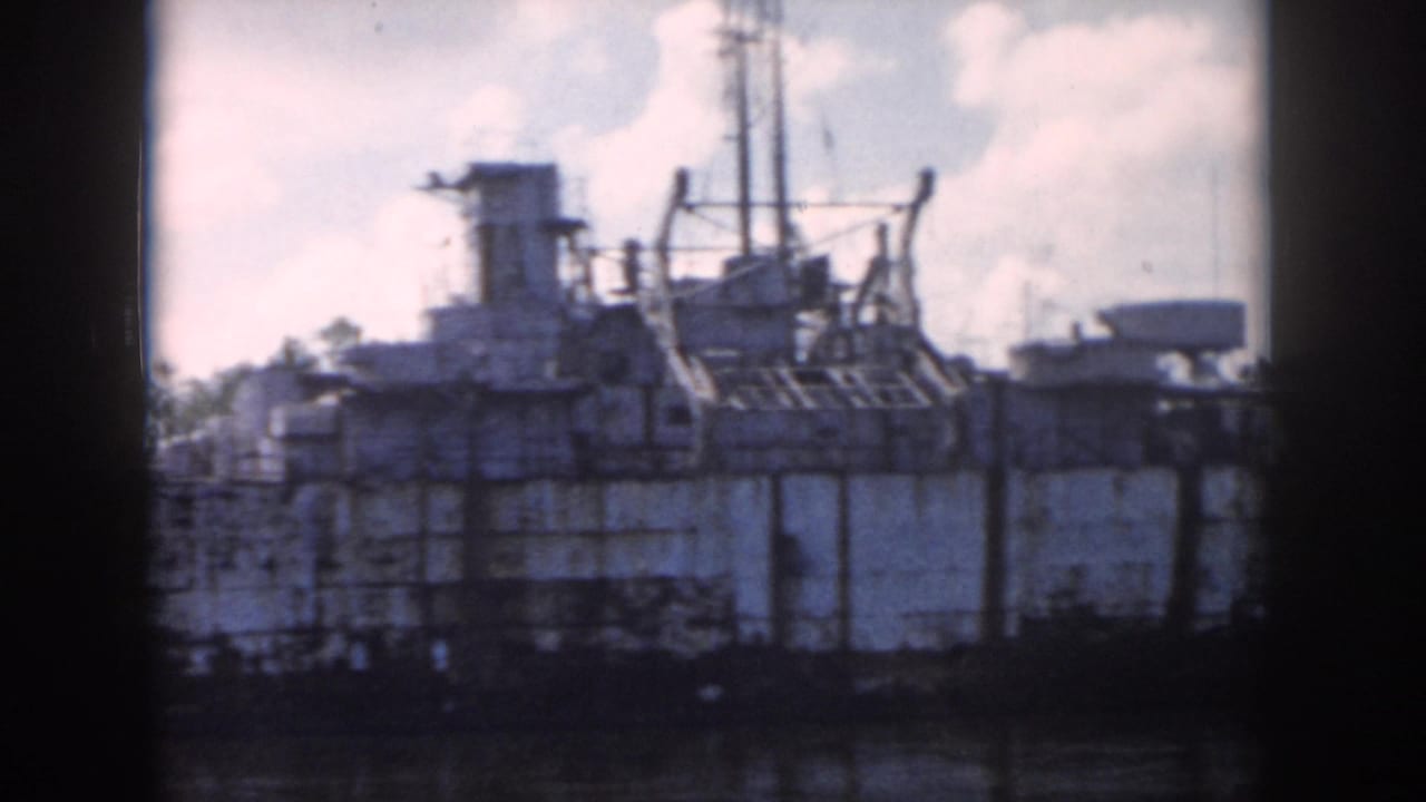 1958 New Orleans 8mm view of a docked weathered ship with deck structures and rigging beside the water.