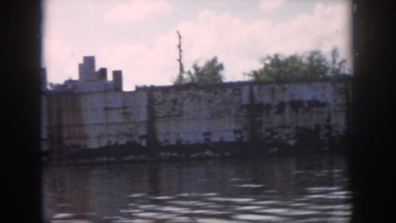 White ship and trees across the river, partly blocked by a dark window post.
