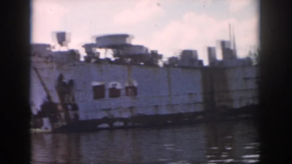 Close river view of a worn white vessel with rusted equipment and industrial shapes on deck in 1958 New Orleans footage.